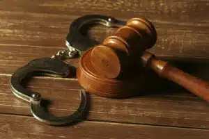 A judge 's gavel and handcuffs on top of a table.