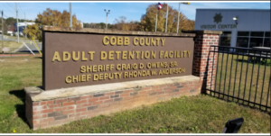 Cobb County Adult Detention Facility entrance sign with the Sheriff's Office building in the background.