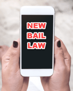 Close-up of a person holding a smartphone with the screen displaying the text 'NEW BAIL LAW' in bold red letters with a white outline